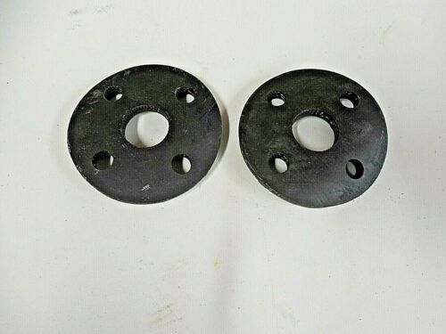 Two black circular metal plates with holes on a white surface.