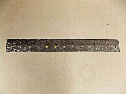 A black metal ruler with white measurement markings on a light surface.