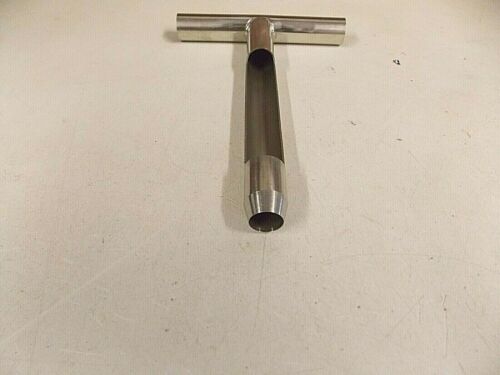 A metal T-shaped razor handle lying on a white surface.