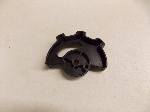 Black plastic gear-like component on a white surface.