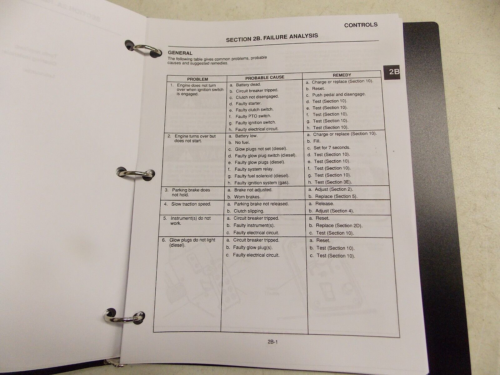 A printed document page with tables and checkboxes, held in a binder.