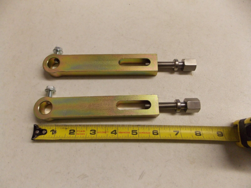 Two metal turnbuckle-like tools with measuring tape below.